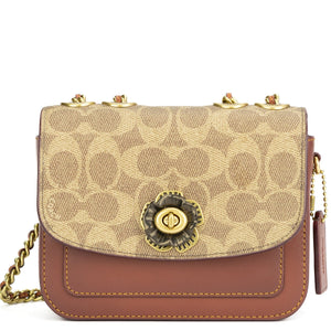 Beige and brown handbag with floral emblem on a white background