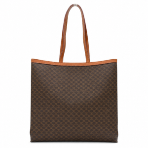 A brown monogram canvas tote bag with tan leather handles and trim, shown against a plain white background.
