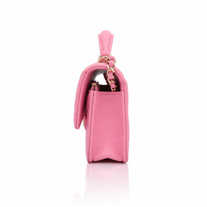 Chanel Mini Top Handle Rectangular Flap Bag in pink lambskin left side view featuring a top handle, gold-tone hardware, and a decorative pink bow charm, set against a clean white background with a soft reflection.