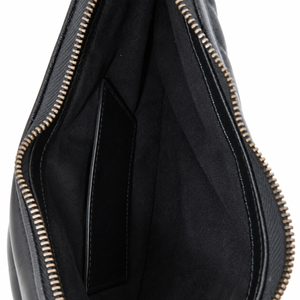 Close-up of the interior of a black leather bag, showing a black fabric slip pocket inside, a black leather exterior flap, and gold-toned metal zippers on a white background.