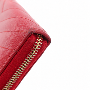 Close-up of a red leather wallet corner with a gold zipper on a white background.