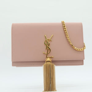A blush pink leather clutch bag with a gold-tone YSL monogram clasp and a matching gold chain strap, displayed on a clean white background.