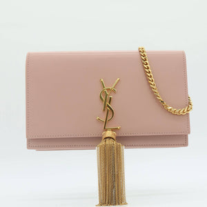 A blush pink leather clutch bag with a gold-tone YSL monogram clasp and a matching gold chain strap, displayed on a clean white background.
