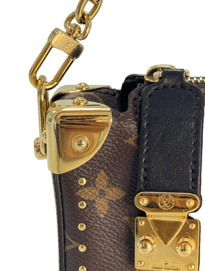 Close-up of a Louis Vuitton monogram handbag showing the brown coated canvas with tan floral motifs, a black leather strap, and gold-tone hardware including a lock, studs, and chain.