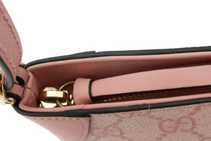 Close-up detail of a pink handbag showing the interior zipper track, gold-tone hardware, and a patterned canvas exterior on a white background.
