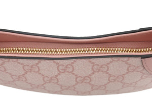 Close-up of a Gucci pouch featuring the brand's signature GG monogram canvas in a dusty pink color, a light pink leather trim, and a gold-tone zipper.
