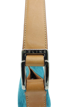 A close-up of a Celine shoulder strap featuring a tan leather strap, a silver-tone metal buckle engraved with 'CELINE', and a textured turquoise blue fabric body visible underneath.