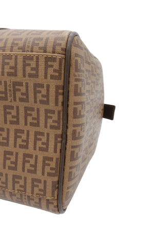 Close-up of a Fendi bag in brown and beige Zucca monogram canvas, showing the side panel and a small dark brown leather tab on a white background.