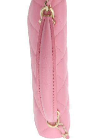 A close-up side view of a pink quilted leather handbag with gold-tone chain and ring hardware, set against a plain white background.