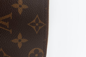 Close-up of a brown monogram patterned material with tan Louis Vuitton-style floral motifs, shown against a white background.