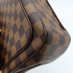 Close-up of a Louis Vuitton handbag in the Damier Ebene canvas, showing the brown and tan checkered pattern and dark brown leather trim against a light gray background.