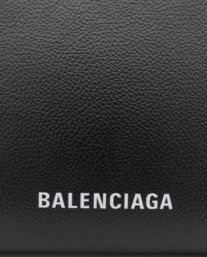 Close-up of a black pebbled leather Balenciaga pouch or wallet with the brand name 'BALENCIAGA' printed in white capital letters on the front.