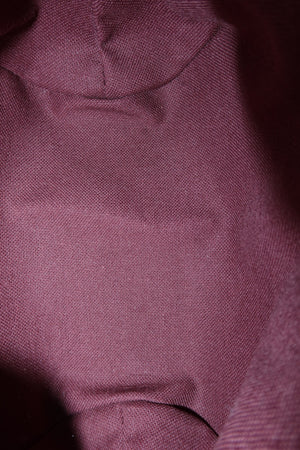 A close-up of textured fabric in a muted dusty rose or mauve color, showing the weave and soft folds.