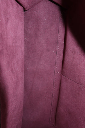 Close-up of a burgundy suede or microfiber fabric surface with stitched panel seams and a soft textured finish.