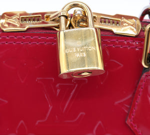 Close-up of a red Louis Vuitton monogram handbag featuring a gold padlock clasp engraved with 'LOUIS VUITTON PARIS'.