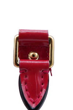 Close-up detail of a glossy red patent leather bag strap with gold-tone hardware and a black underside, showing part of a matching red monogram patterned body.