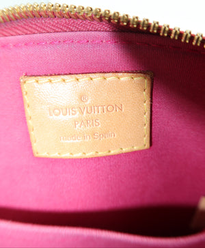 Close-up of a Louis Vuitton interior pouch showing a bright pink fabric lining, a gold zipper, and a tan leather brand patch with 'LOUIS VUITTON PARIS made in Spain' text.