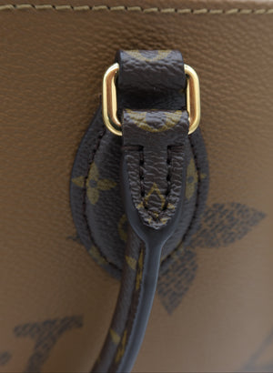 Close-up detail of a Louis Vuitton handbag showing the dark brown monogram canvas strap attached with gold-tone hardware to a tan leather body.