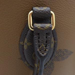 Close-up detail of a Louis Vuitton handbag showing the dark brown monogram canvas strap attached with gold-tone hardware to a tan leather body.