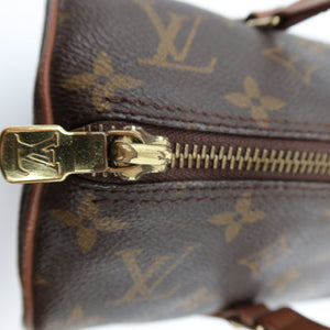 Close-up of a Louis Vuitton monogram canvas bag with a gold-tone metal zipper pull and zipper track on a white background.