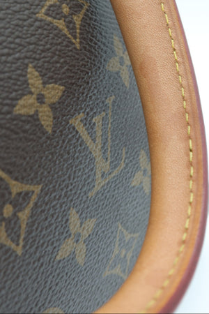Close-up detail of a Louis Vuitton monogram canvas bag corner showing the brown coated canvas with tan monogram print and a contrasting light brown leather trim with yellow stitching.