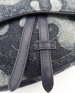 Close-up of a textured canvas bag with a dark navy blue leather strap and trim, featuring a gray and white abstract pattern.