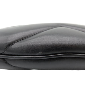Close-up of a black leather pouch or clutch showing the quilted stitching and textured leather surface against a white background.