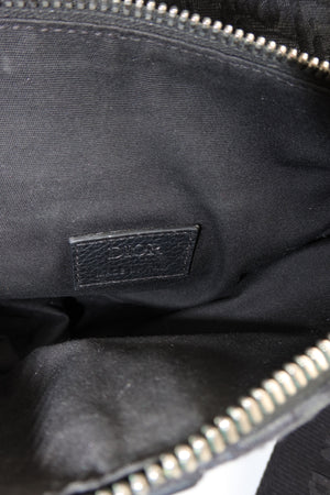Close-up of the interior of a black Dior bag, showing a black leather brand patch with embossed Dior text and silver-tone zipper trim.