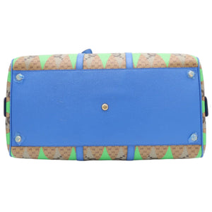 A Gucci duffle bag shown from the bottom, featuring a vibrant blue base with brown and green monogram patterned trim.