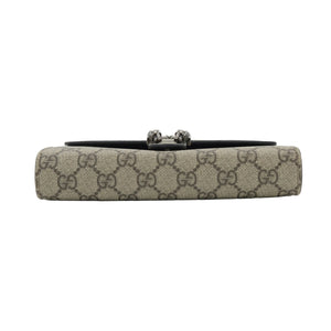 A Gucci clutch bag in beige GG Supreme canvas with a black leather band and a silver-tone horsebit clasp, shown against a plain white background.