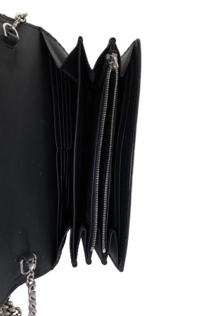 A close-up of a black multi-compartment wallet or clutch shown open, displaying its interior card slots, zippered pocket, and silver-tone chain strap on a white background.