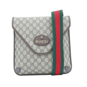 A small Gucci flap bag in beige GG Supreme canvas with brown leather trim and a green and red web stripe detail, shown on a plain white background.