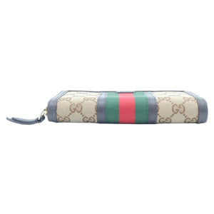 A Gucci zip-around wallet in beige GG Supreme canvas with the signature green and red web stripe down the center, finished with blue-gray leather trim and a blue-gray wristlet strap.