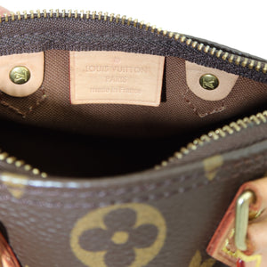 Close-up of the interior of a Louis Vuitton handbag in the classic brown monogram canvas, showing the tan leather interior label and gold-tone hardware.