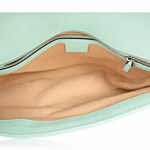 Close-up of the interior of a mint green clutch or pouch, showing a tan fabric lining and a silver zipper with a mint green pull tab.