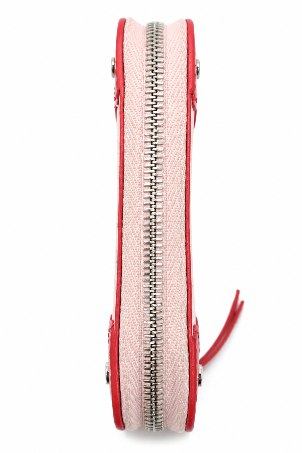 A close-up side view of a light pink canvas zippered pouch with red leather trim and a silver metal zipper, shown on a plain white background.
