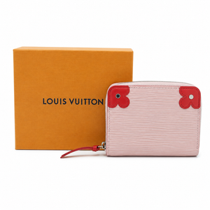 A Louis Vuitton zip-around wallet in pale pink Epi leather with signature red flower corner details, shown next to its orange Louis Vuitton box on a white background.