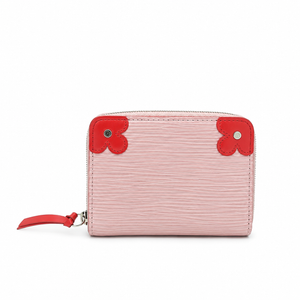 A light pink textured leather zip-around wallet with bright red leather clover-shaped corner accents and a matching red zipper pull, shown on a plain white background.