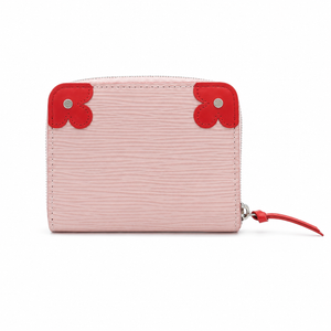 A light pink textured leather zip-around wallet with bright red leather corner accents and a matching red zipper pull, shown on a plain white background.