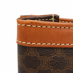 Close-up detail of a brown monogram leather accessory, showing a tan leather trim band with white stitching and a dark brown patterned body on a white background.