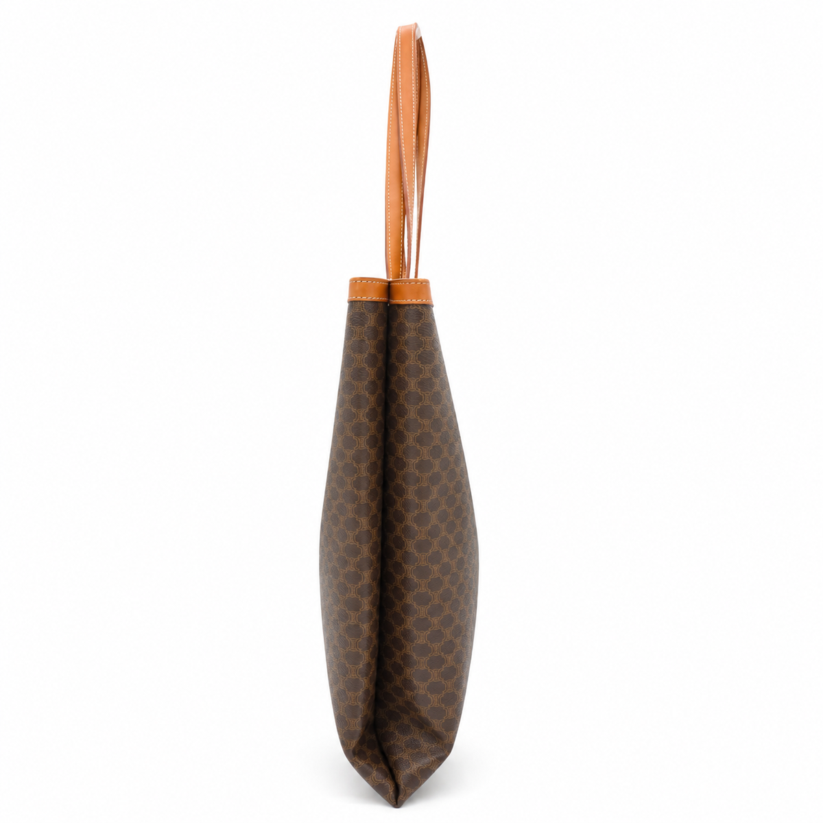 A brown coated canvas tote bag with a repeating monogram pattern and a light brown leather handle, shown from the side against a white background.