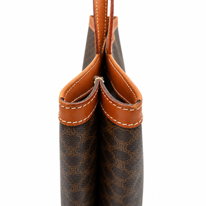 Close-up of the top edge of a brown monogram handbag with tan leather trim and white stitching, shown against a plain white background.