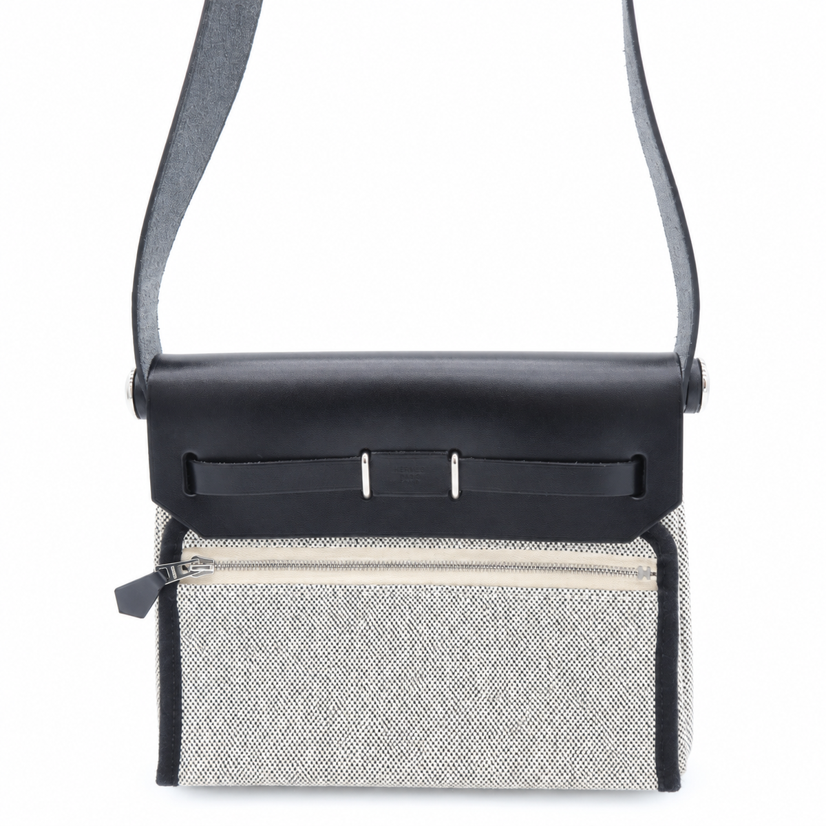 A structured crossbody bag with a black leather flap and shoulder strap, paired with a textured light gray woven front panel and a zippered pocket.