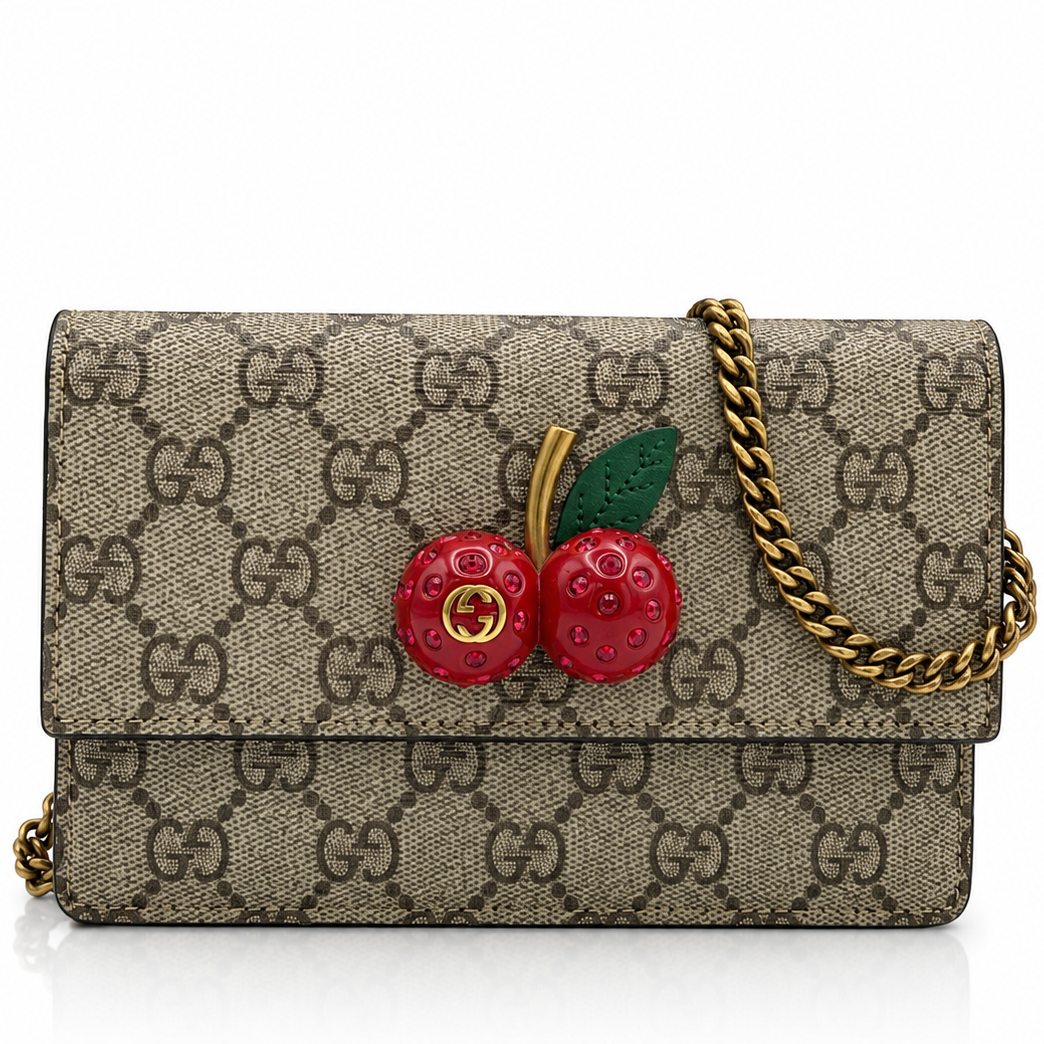 Gucci GG Supreme Monogram Mini Cherry Chain  shoulder bag with a gold chain strap and a 3D cherry embellishment on the front, shown on a white background.
