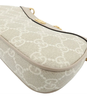 Close-up of a beige and off-white monogram handbag corner with gold-tone hardware on a white background.