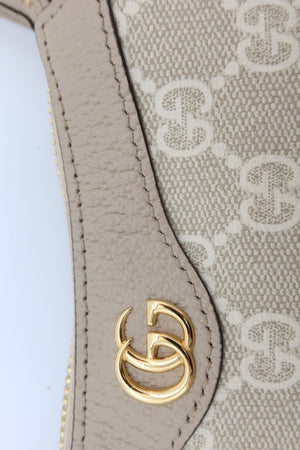 Close-up of a Gucci handbag featuring beige and off-white GG Supreme canvas with a beige leather trim and a gold-tone interlocking GG logo clasp.
