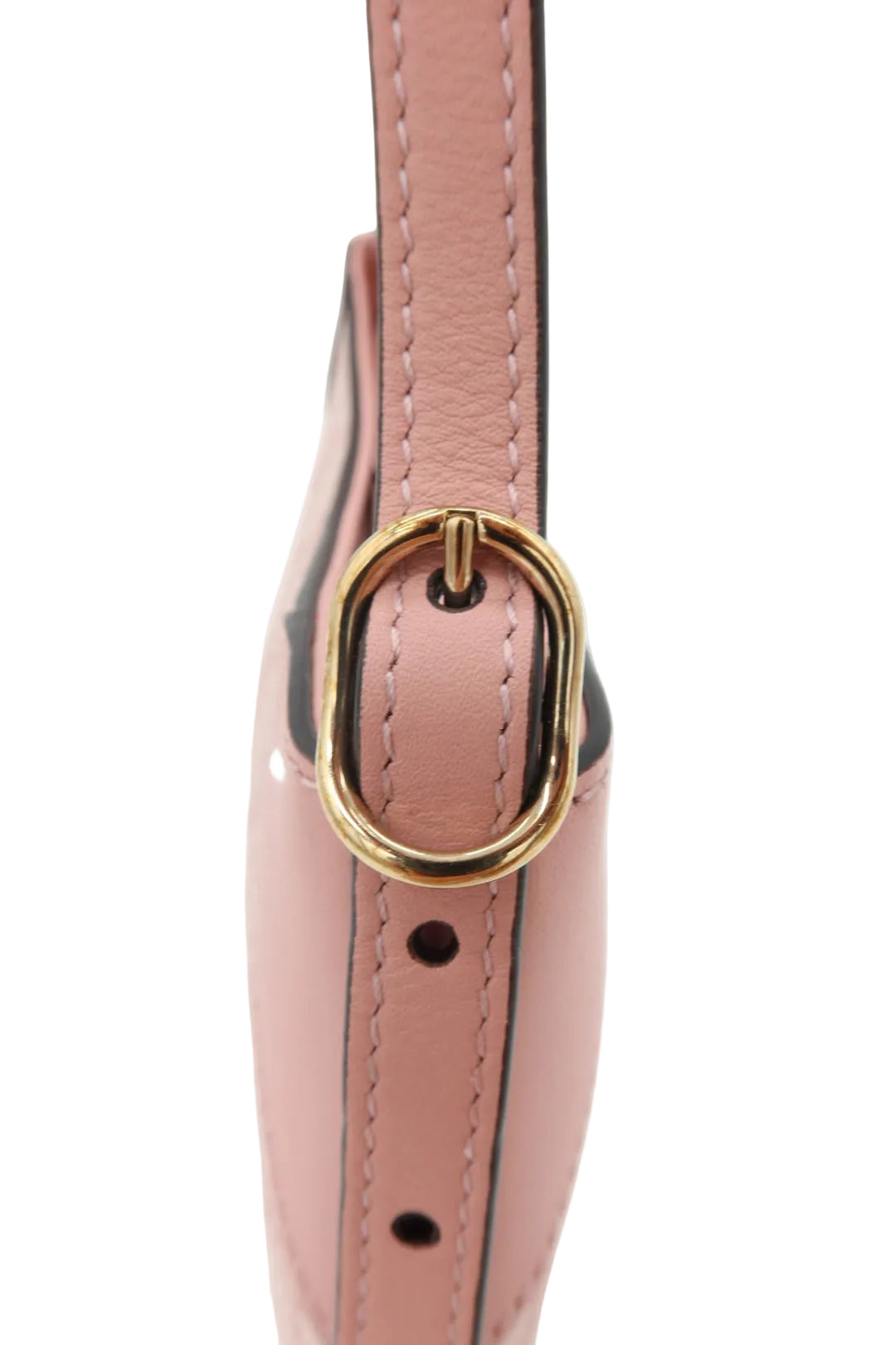 Close-up of a light pink leather strap with gold-tone metal hardware and black contrast stitching, shown against a plain white background.