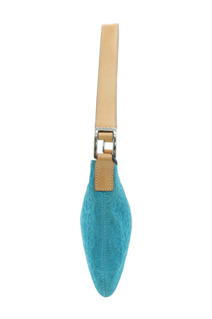 A turquoise blue monogrammed shoulder bag with a tan leather strap and silver-tone hardware, shown from a side profile view against a light blue background.