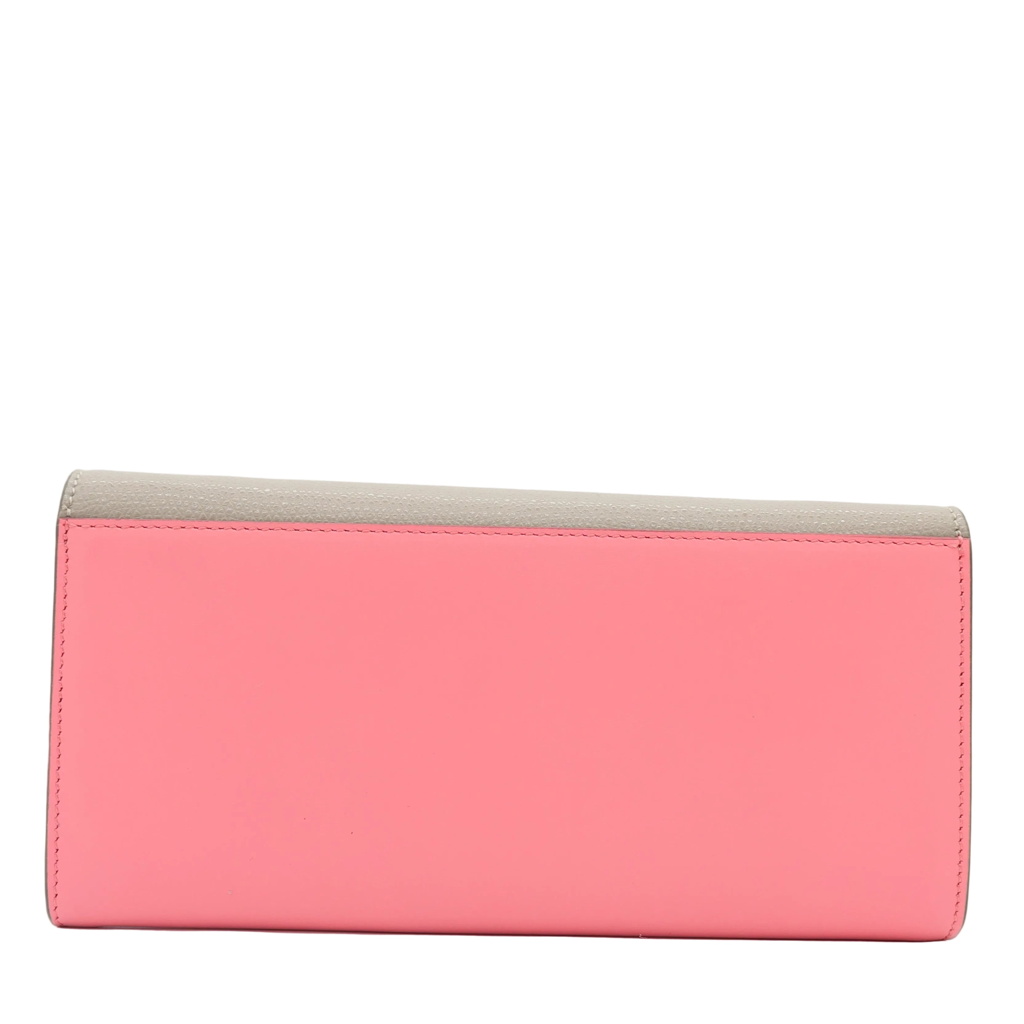 A rectangular clutch wallet in two-tone color-blocked leather, featuring a vibrant pink front panel and a light beige top flap, set against a plain white background.