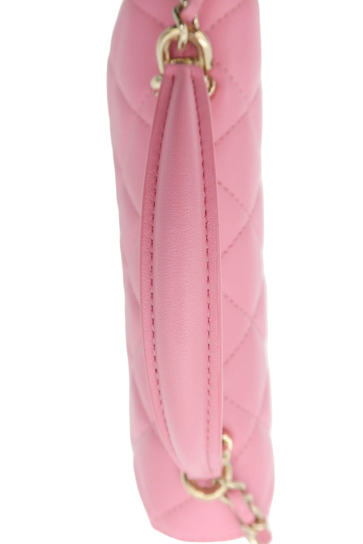 A close-up side view of a pink quilted leather handbag with gold-tone chain and ring hardware, set against a plain white background.